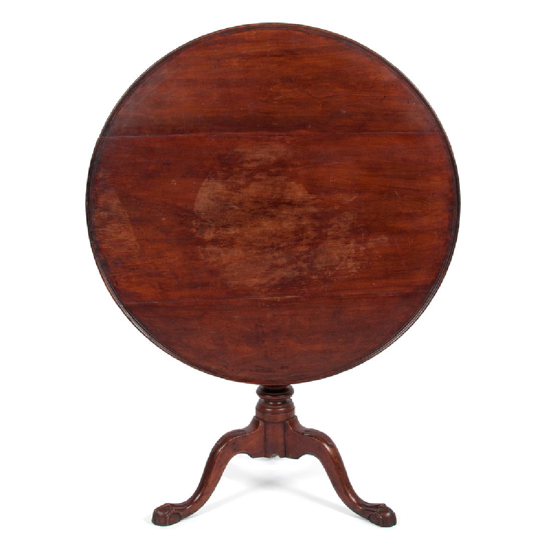 Chippendale Tilt Top Table in Walnut: American, late 18th-early 19th century. A Chippendale tilt top table in walnut, having a round top over a birdcage support, baluster and ring turned standard, rising on tripod shell cabriole