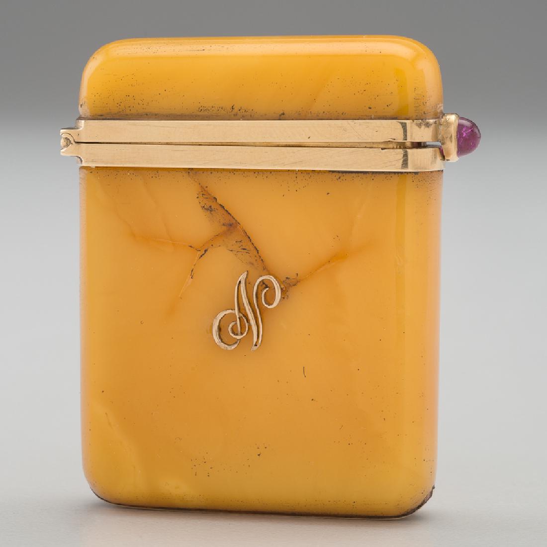 Amber and 18 Karat Gold Match Safe: French. An amber match safe with 18 karat gold mounts and a ruby lift, with match strike to underside, marked to interior rim with French hallmarks; ht. 2, wd. 1.5, dp. 0.5 in. Provenance: Property fr