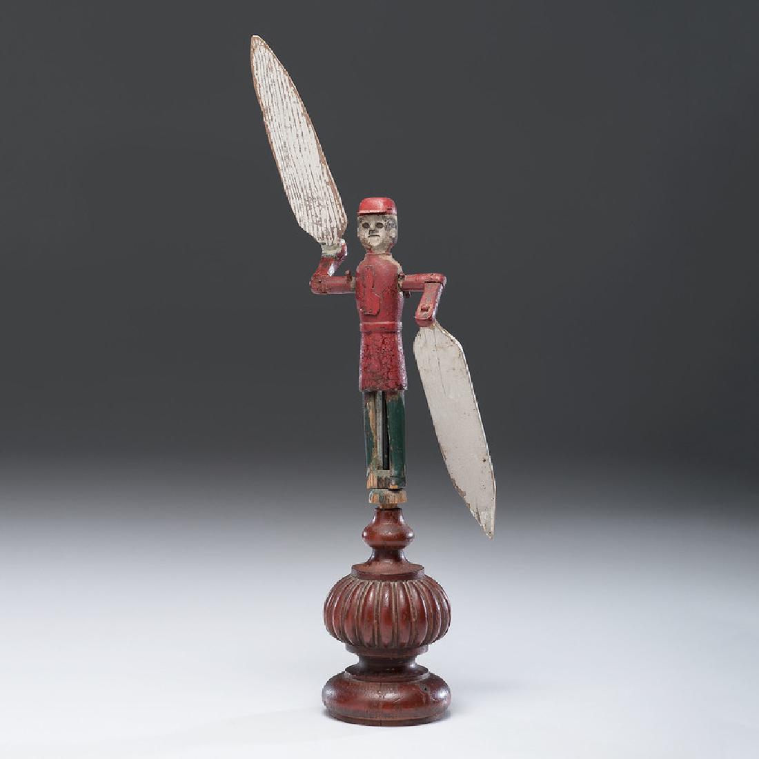 Folk Art Whirligig: American, 20th century. A wooden and metal painted whirligig, with stand; oah. 21.25 in. (including stand, with paddle up), figure ht. 9 in.