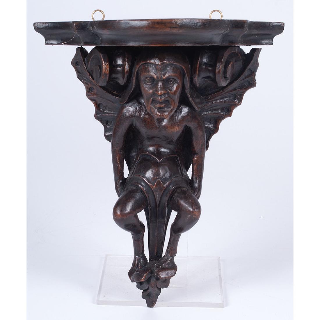 Black Forest-style Carved Wall Bracket: Late 19th-early 20th century. A wooden carved wall bracket in the form of a grotesque figure; ht. 11.25, dp. 5 in.