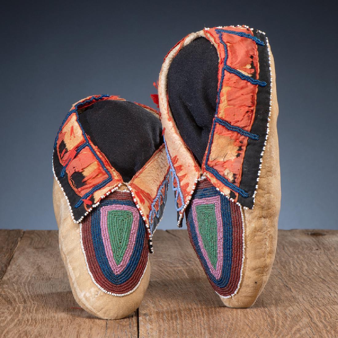 Lenape (Delaware) Beaded Hide Moccasins: thread-sewn and beaded on vamps in colors of rose, deep translucent blue, pink, and pea green; cuffs with red and black silk, length 9.25 in. third quarter 19th century