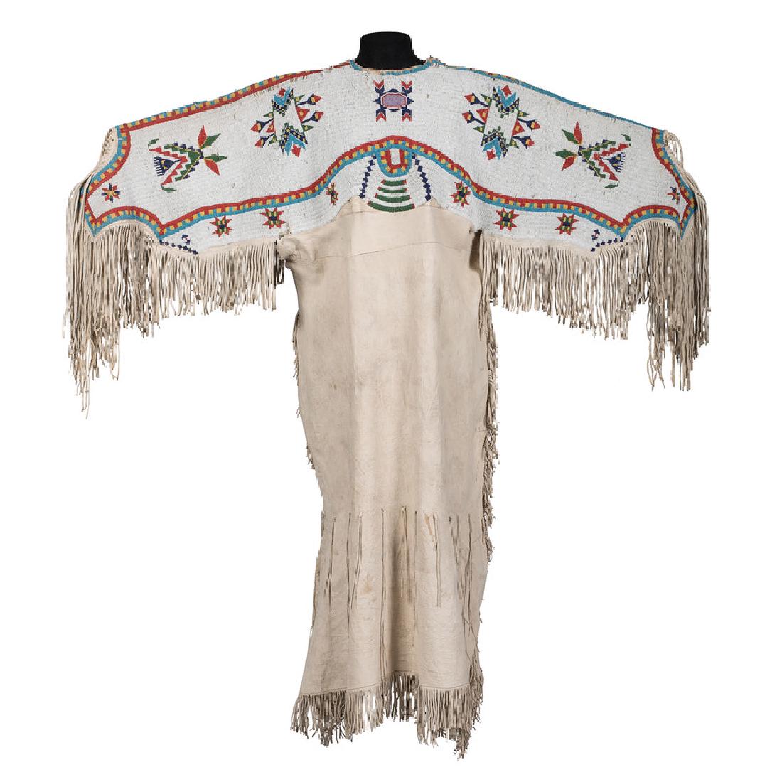 Sioux Beaded Hide Dress: thread and sinew-sewn; yoke beaded in colors of apple red white-heart, pea green, light and dark blue, greasy yellow, and pink; soft fringe falls from sleeves and lower hem of dress, length 53 in. x c