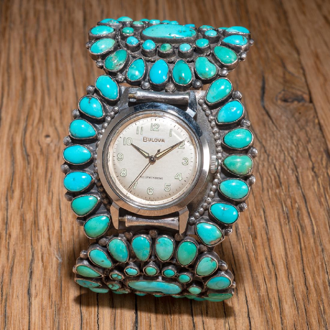 Navajo Sterling Silver and Turquoise Cluster Watch Cuff: turquoise clusters intertwine with silver rope surround a central Bulova watch face; interior circumference 6 in., gap length 1.5 in., weight 72.9 dwt mid-20th century