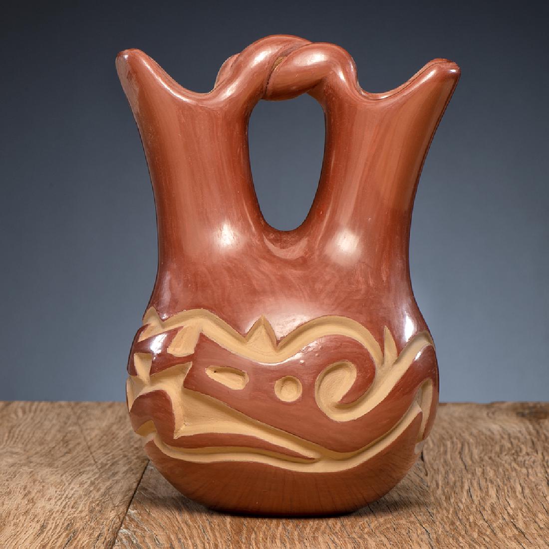 Helen Shupla (Santa Clara, 1928-1985) Carved Redware: rounded body carved with an undulating Avanyu; two spouts connect by a twisted handle; signed on base, height 7.5 in. x diameter 5.75 in. third quarter 20th century
