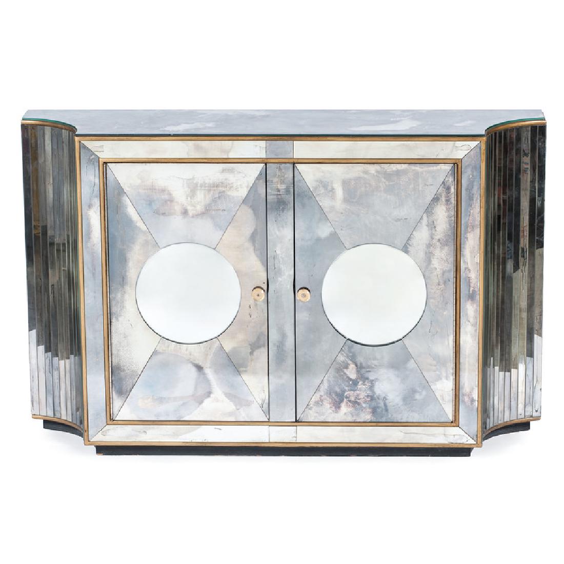 Art Deco Commode: Possibly Continental, 20th century. An Art Deco mirrored commode with brass trim, having a shaped top over conforming body, two hinged doors and interior shelves, raised on a conforming black base; ht