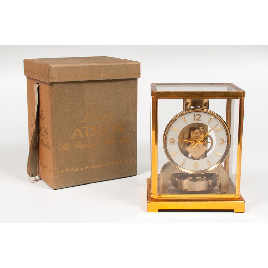 1950s LeCoultre Atmos Clock with Carrying Case: Swiss, 1950s. A LeCoultre Atmos brass and glass mantle clock with round face, serial number 121955 . Original green cloth covered carrying case and wall shelf included; clock ht. 8.75, wd. 7, dp. 5.2