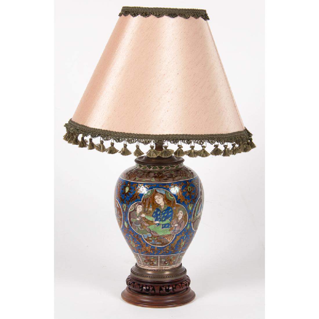 Persian Earthenware Lamp: Persian. A glazed ceramic vase mounted as a lamp, having painted polychrome decoration of figures, animals and foliage, resting on carved wooden pedestal base; oah 30.25 in., dia. of lamp 10 in.