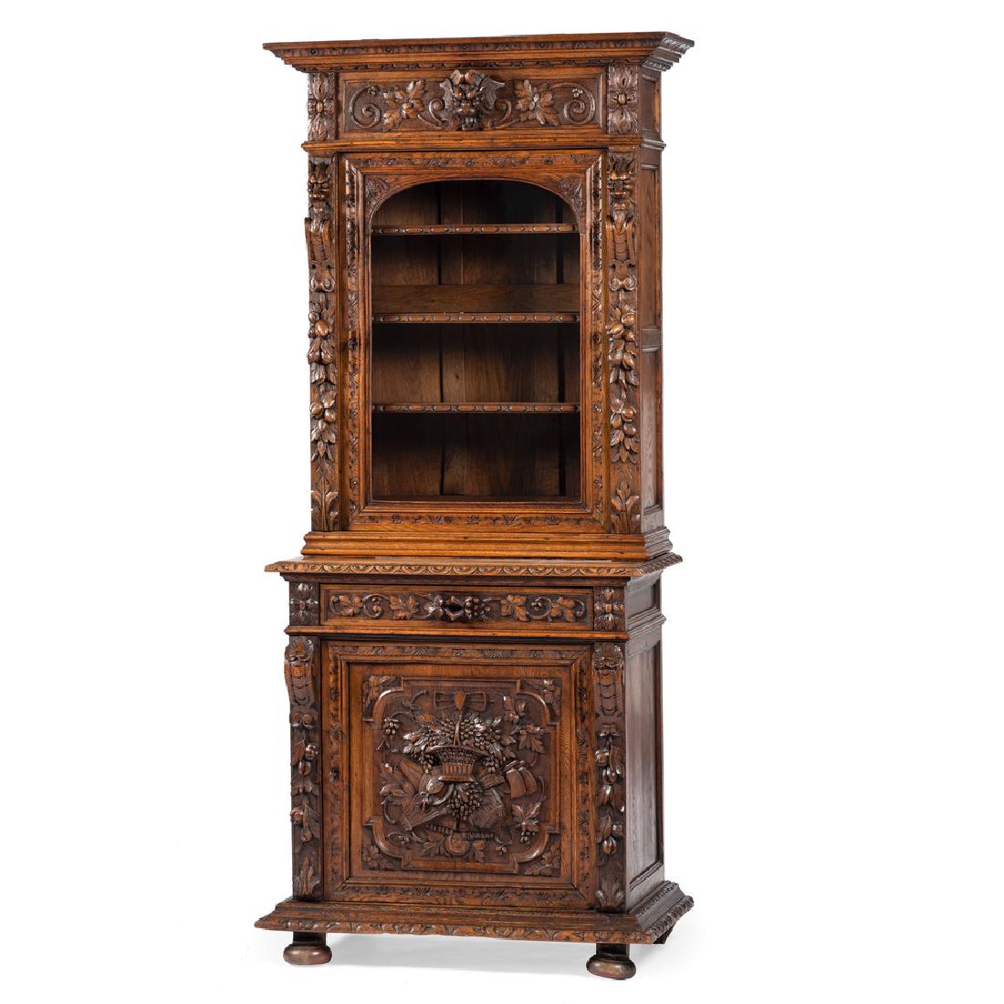 Continental Carved Oak Bookcase: Continental, 19th century. A two-piece carved bookcase in oak, the upper section having a carved and molded cornice over a figural carved frieze flanked by rosette carvings, the paneled case with cent