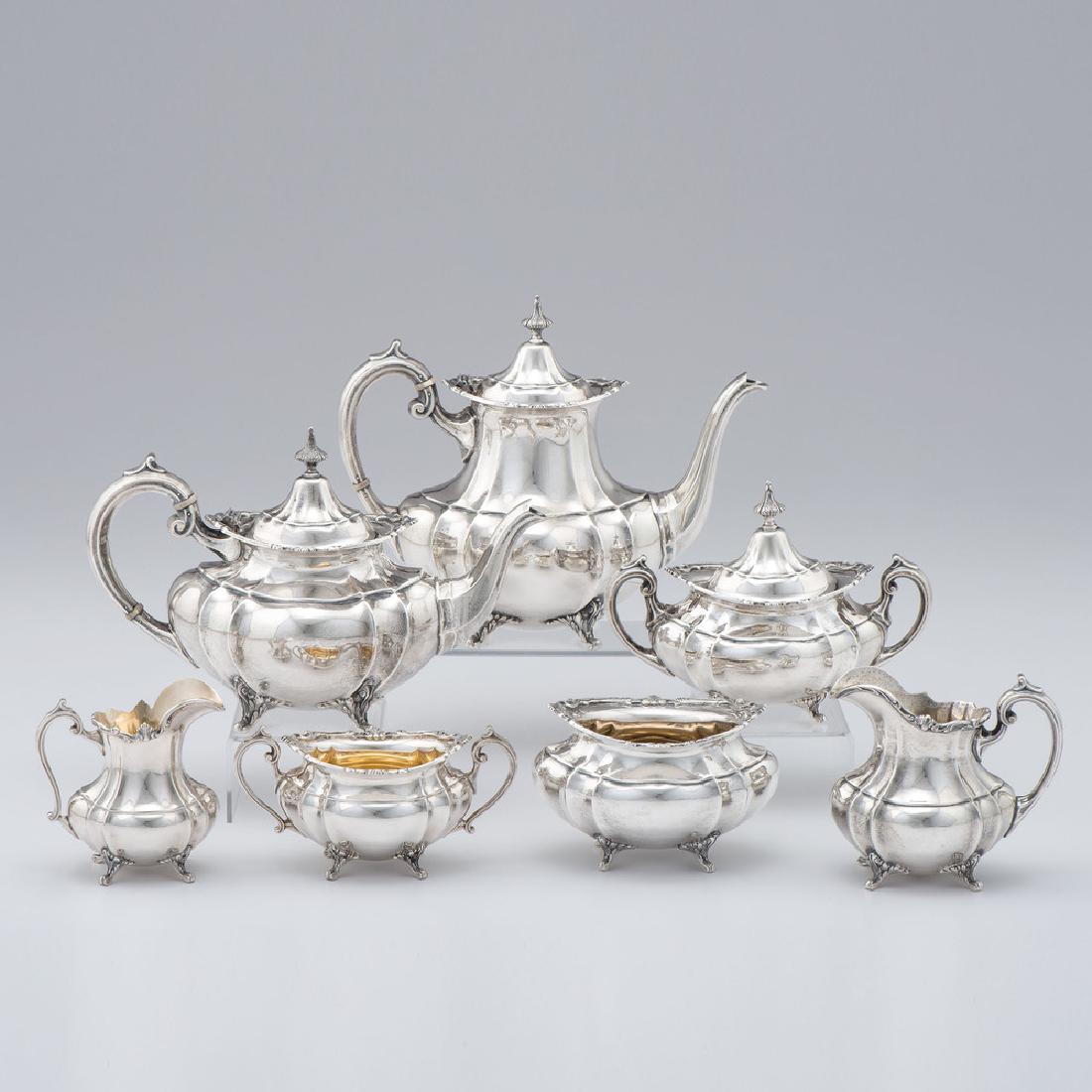 Reed & Barton Sterling Seven-Piece Tea and Coffee: American, 1949. A seven-piece sterling silver Reed & Barton service in the Hampton Court pattern, including a tea pot, coffee pot, a lidded sugar, two cream pitchers and two open waste bowls. Each p