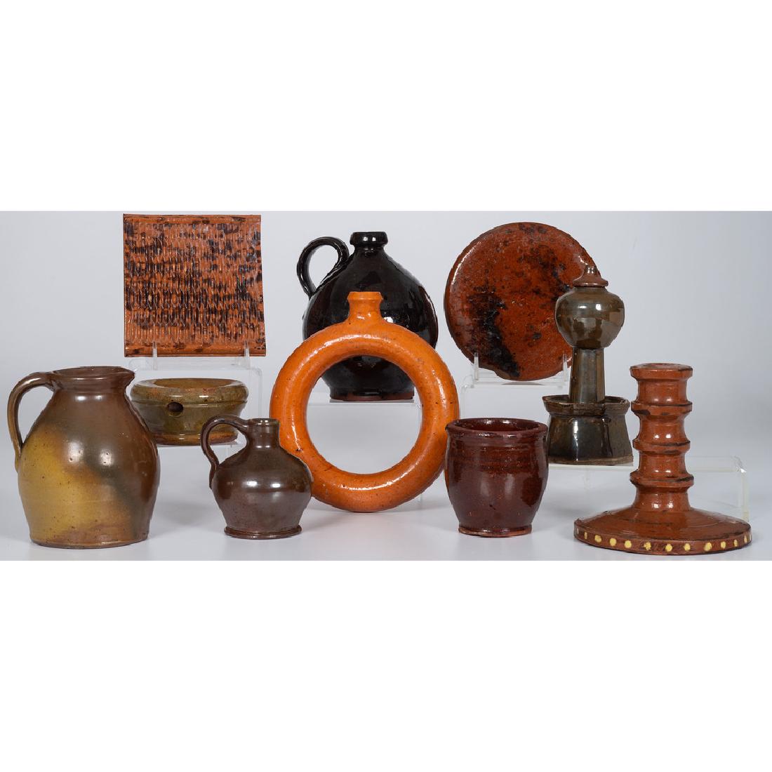 Redware Jugs, Trivets and Other Items: American, 19th-20th century. A group of redware including two trivets, three jugs, a ring flask, a jar, a spittoon, a candlestick and an oil lamp; largest ht. 7 in. Provenance: Property from the Ameri