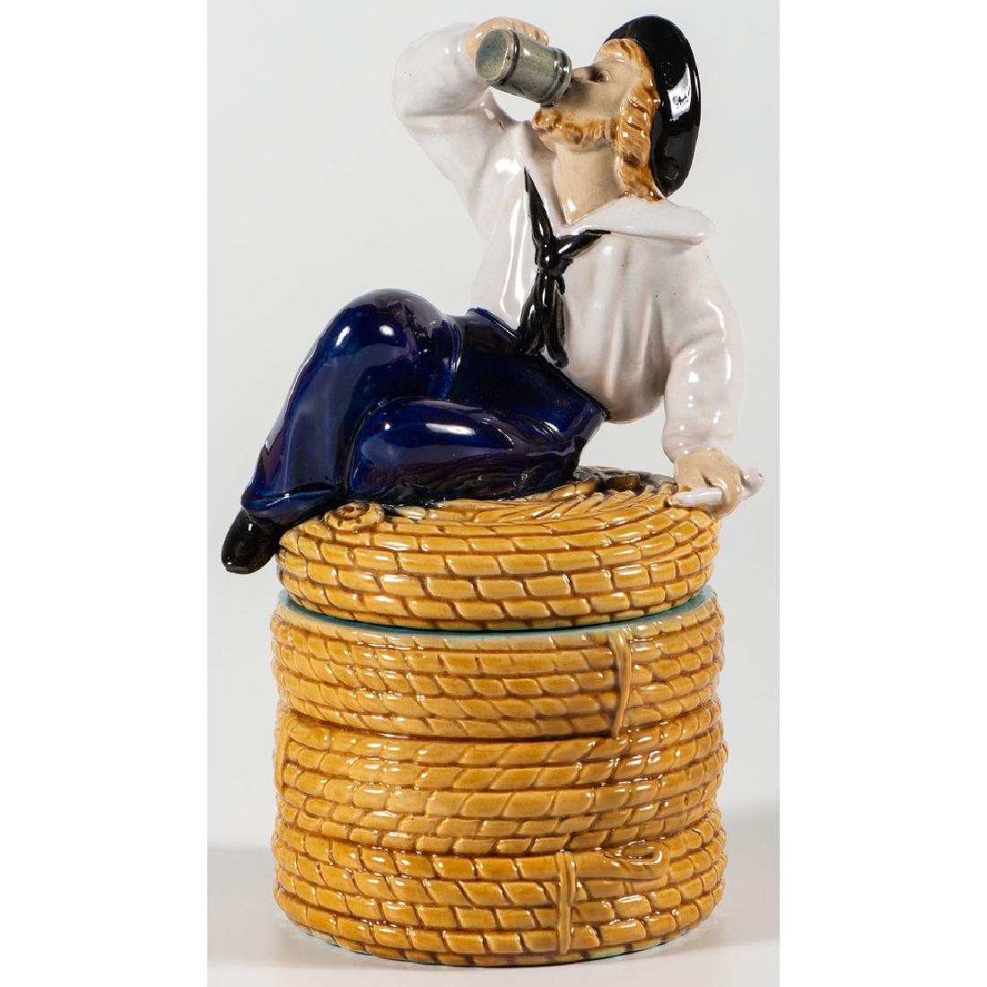 Minton Majolica Tobacco Jar: English, 19th century. A majolica tobacco jar in the form of coiled rope, the lid with figure of a drinking sailor. Impressed mark to underside, with painted mark R to lid and bottom; ht. 9 in.