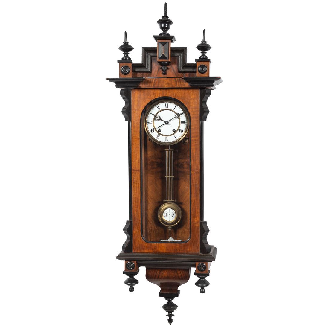 Victorian Wall Clock: American 19th century. A Victorian hanging wall clock in mahogany with pine secondary, having a stepped and molded removable crest with carved panels and turned finials, the open pane pendulum door wi