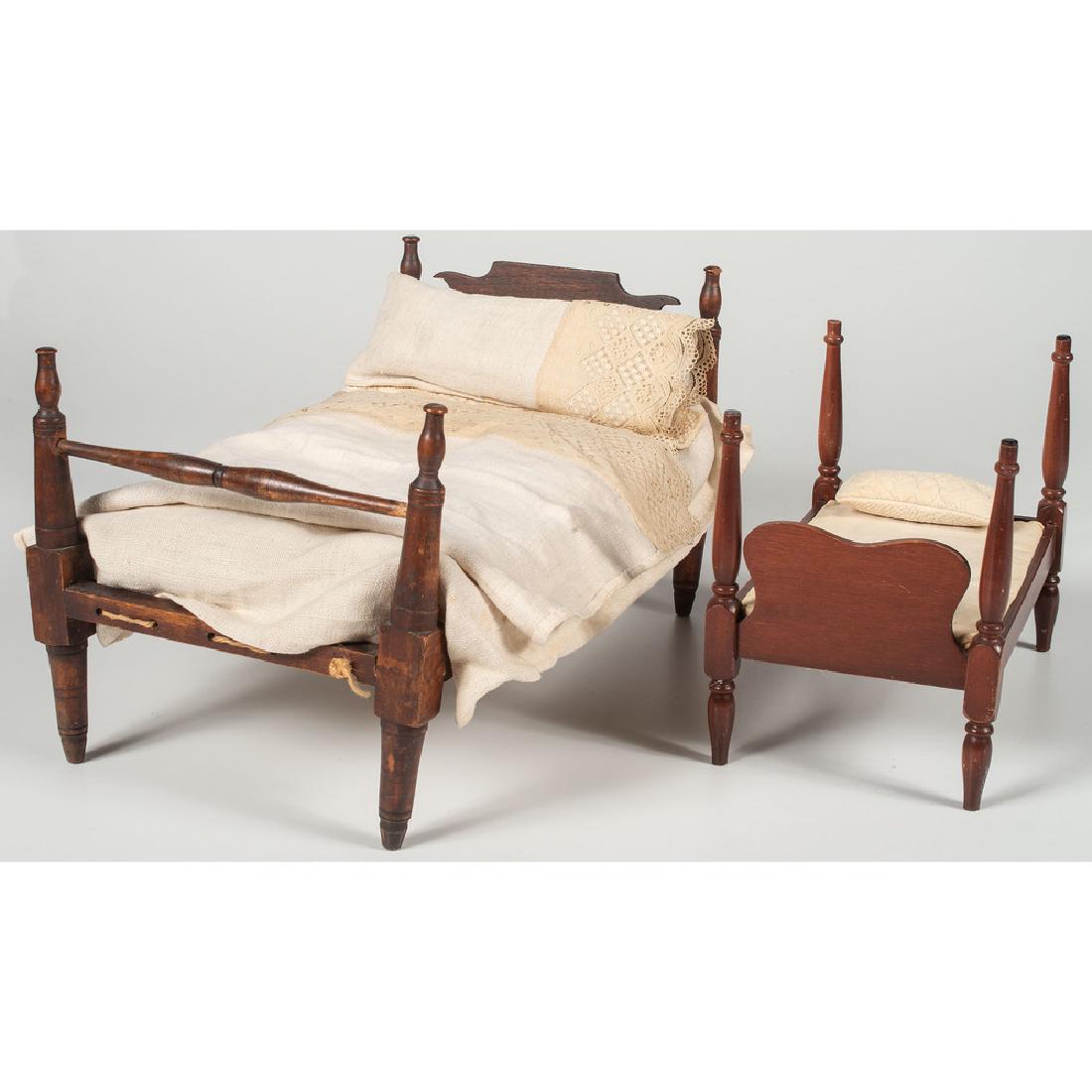 Miniature Beds: American, 19th-20th century. Two miniature beds including a rope bed with mattress and linens; larger ht. 10.25, lg. 18, wd. 11 in. Provenance: Property from the Americana Collections of Kenneth and B
