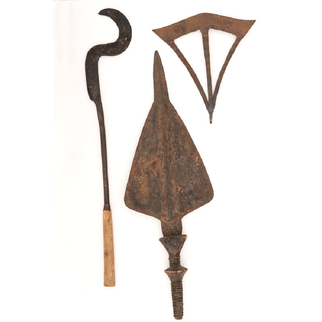 Lot of Three African Weapons: Lot consists of three edged weapons of African origin, including one 10.5" x 9.5" Songye ax head with figural motifs, one triangular sword with 17.25" blade (possibly Congolese), and one scythe weapon