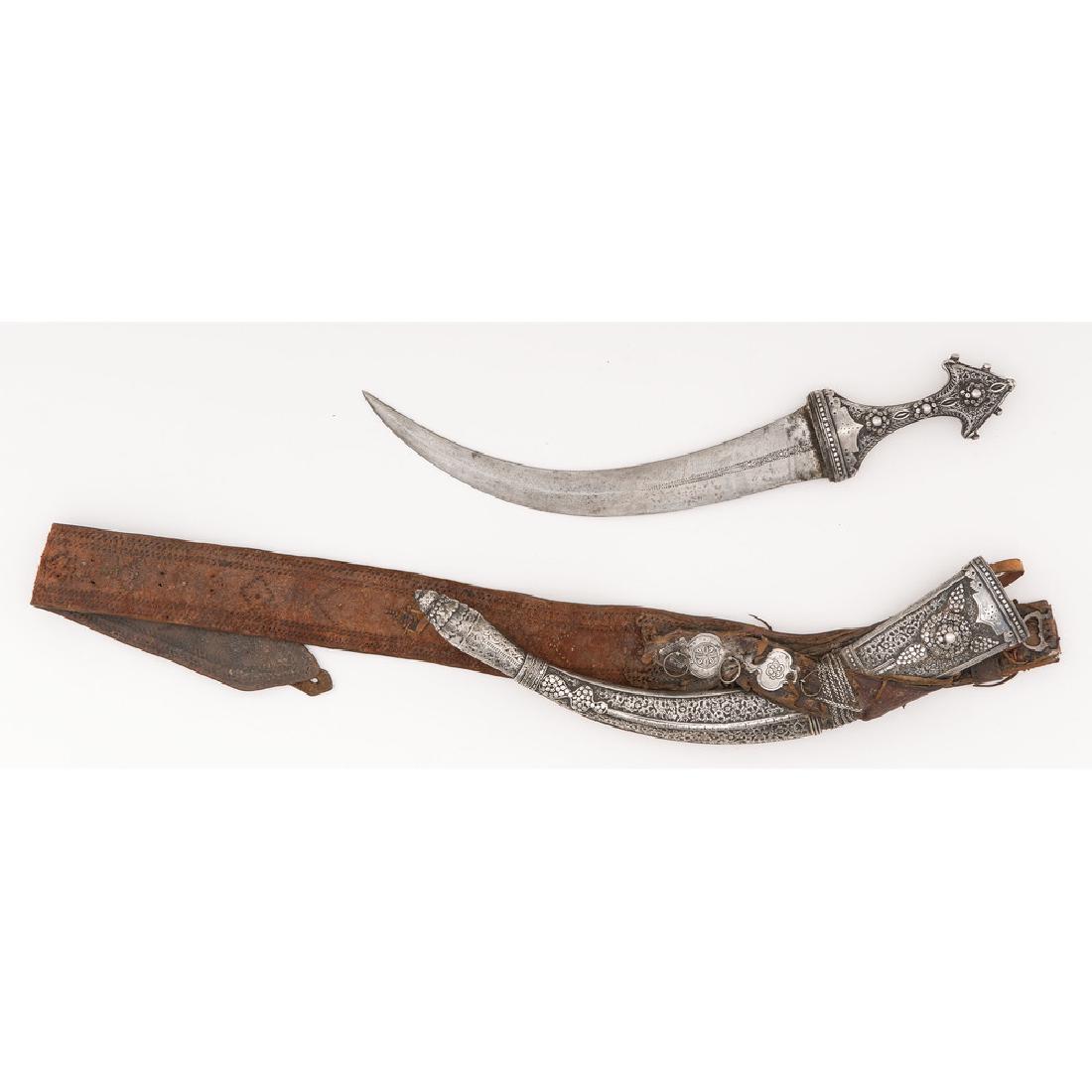 Fine Silver Mounted Saudi Jambiya with Belt: 12.75" double edged blade, 18" overall length, silver mounted. Hilt is of a triangular form with raised silver ornaments including three silver rosettes on grip, repeated as a central theme of scabb