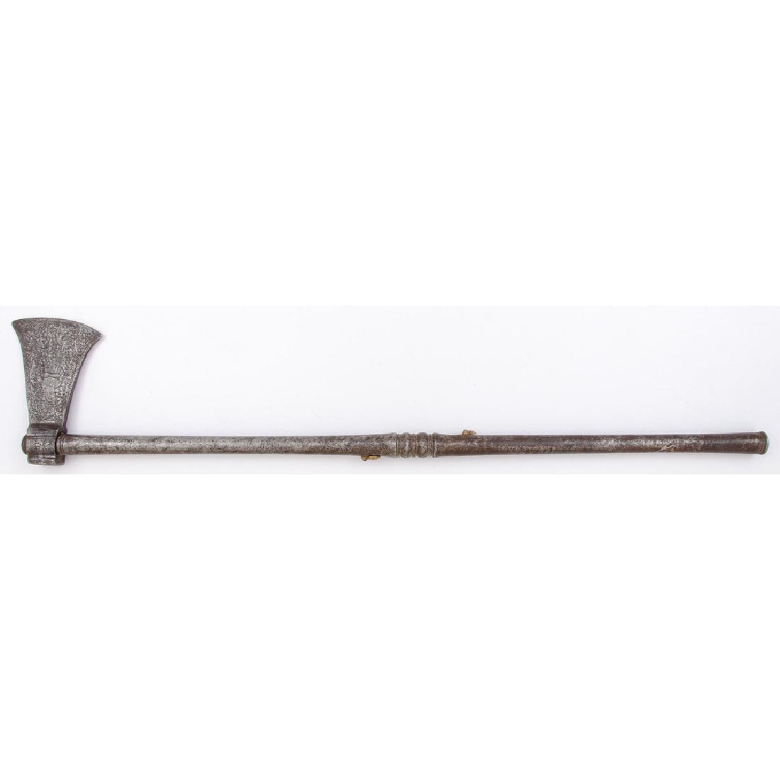 Mughal Axe/Matchlock Combination Weapon: 26.75" overall length, blade 3.25" at widest point. Features two approximately .45 caliber barrels along vertical axis. Brass touch hole covers. Blade engraved with floral and figural motifs.