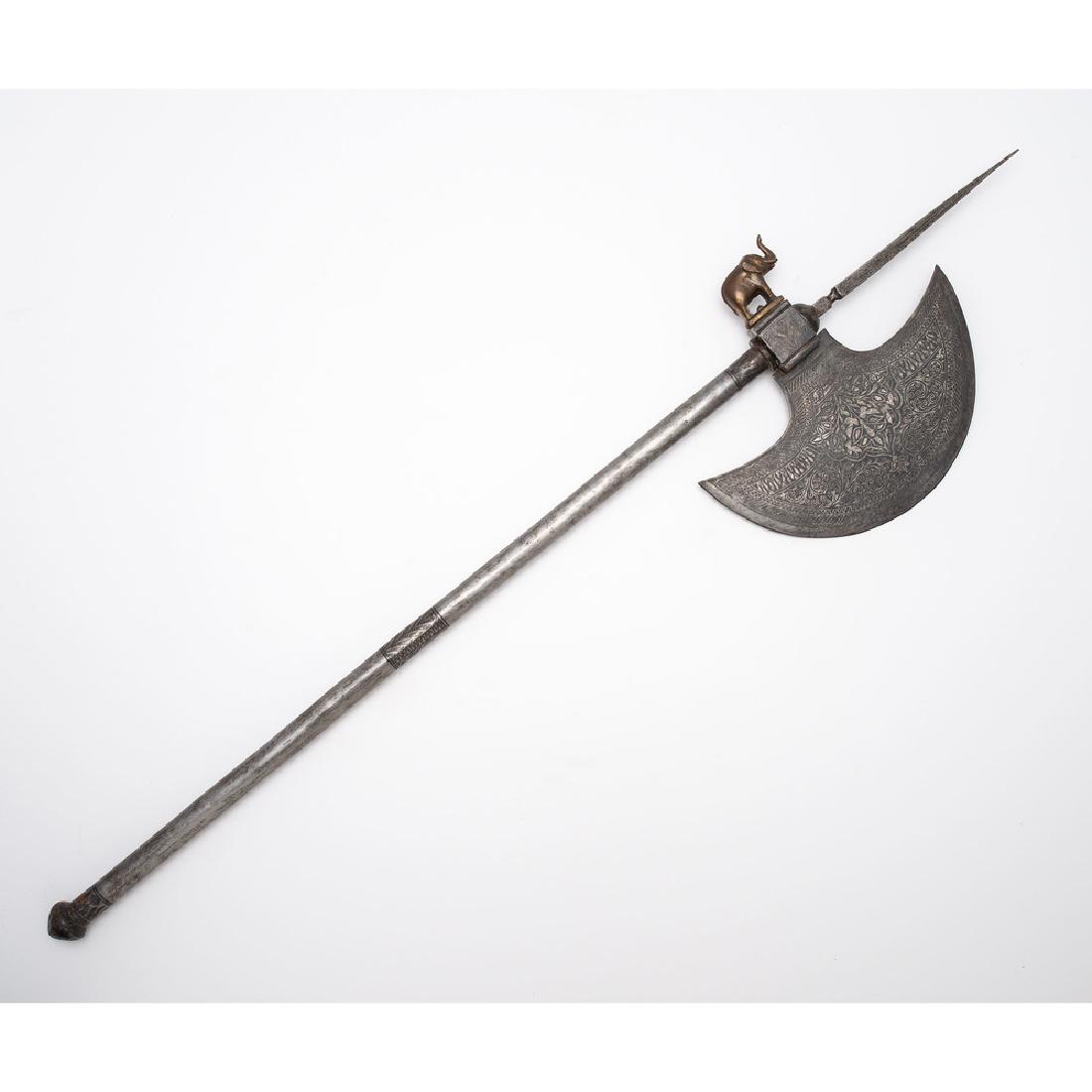 Indo-Persian battle Axe: 31.5" x 8". Blade engraved with vine work and floral motifs of typical form with brass elephant on rear. Additional engraving on haft.