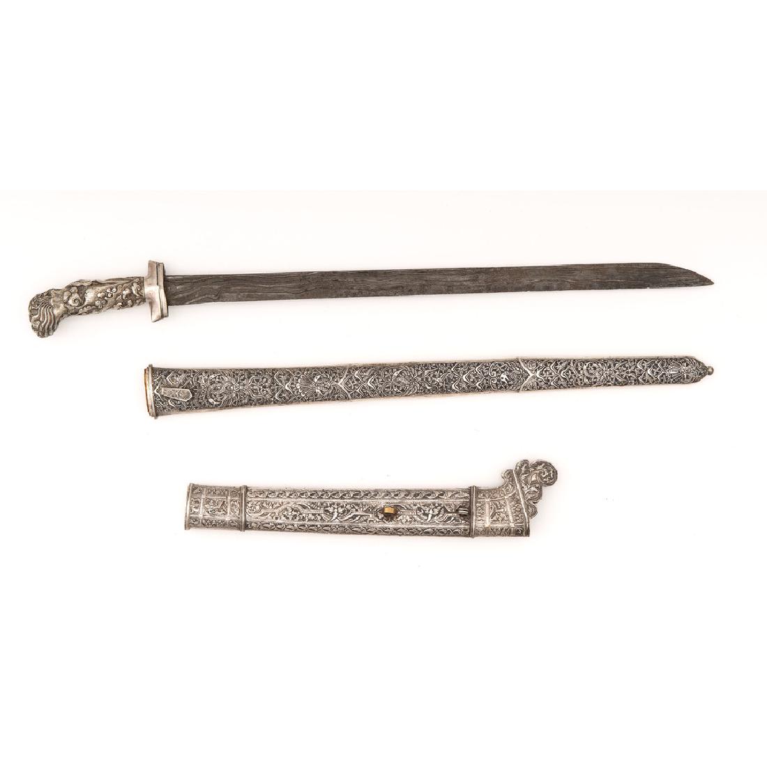 Indonesian Pedang and Scabbard: Lot includes one Indonesian pedang with 20.5" single edged blade showing a basic pamor (pattern) and a silver-washed hilt. Also includes metal-covered wood scabbard with traditional geometric and 