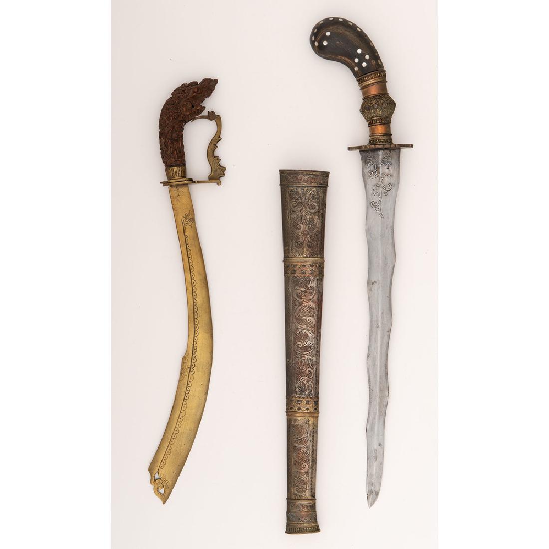 Lot of Two Southeast Asian Edged Weapons: Lot consists of one Moro gunong sword with 16.25" blade and gilt comprised of water buffalo horn with mother of pearl inserts. Ornately engraved scabbard shows some traces of gold wash. Also inclu
