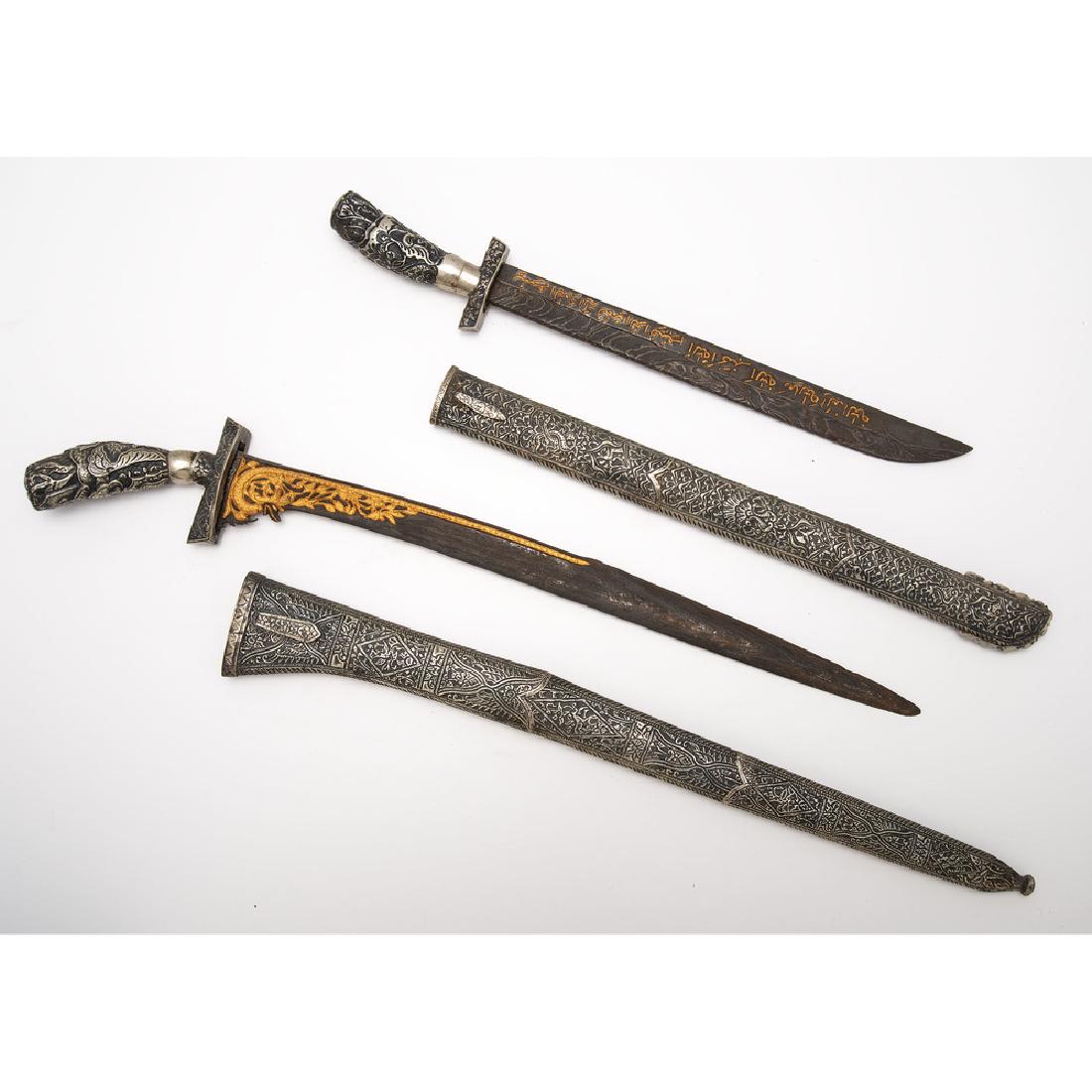 Lot of Two Indonesian Pedang: first item 26.5" overall, 19" blade. Silver handle heavily decorated with floral motifs. Blade has typical Indonesian pamor pattern with gold gilt naga on the hilt of both sides. Second item 22" overa