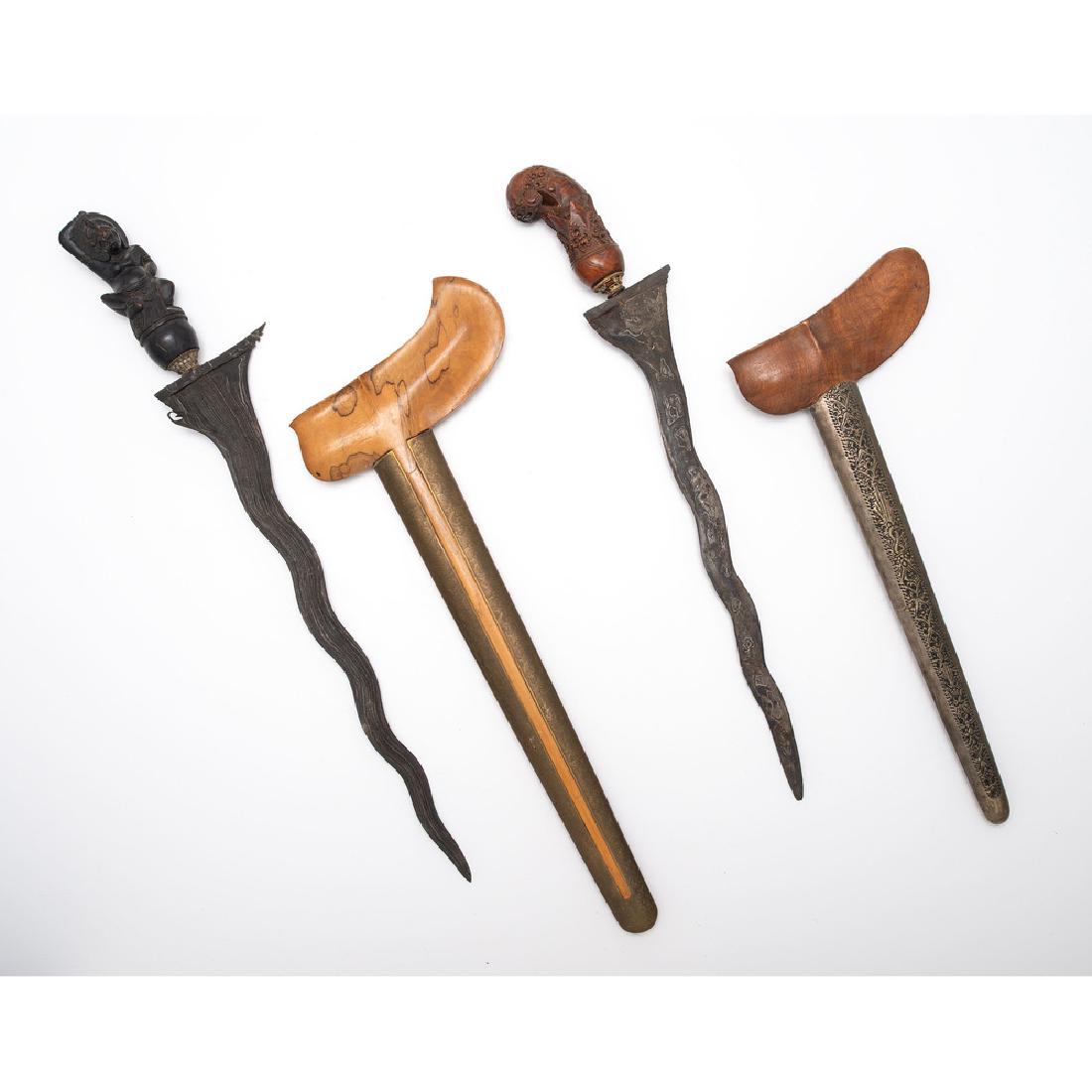 Lot of Two Indonesian Keris: Lot consists of two kerises, one with 13.75" blade with nine luks (waves) and figural grip, likely of Balinese origin. Wood scabbard with brass cladding engraved with floral motifs. Also include