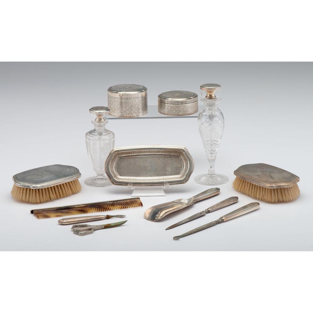 Tiffany & Co Sterling-Mounted Dresser Set: American, ca 1920s. A seventeen-piece dresser set mounted with Tiffany sterling silver, including a hand mirror, five brushes of varying size, a comb, two cut glass scent bottles, two lidded dresser j