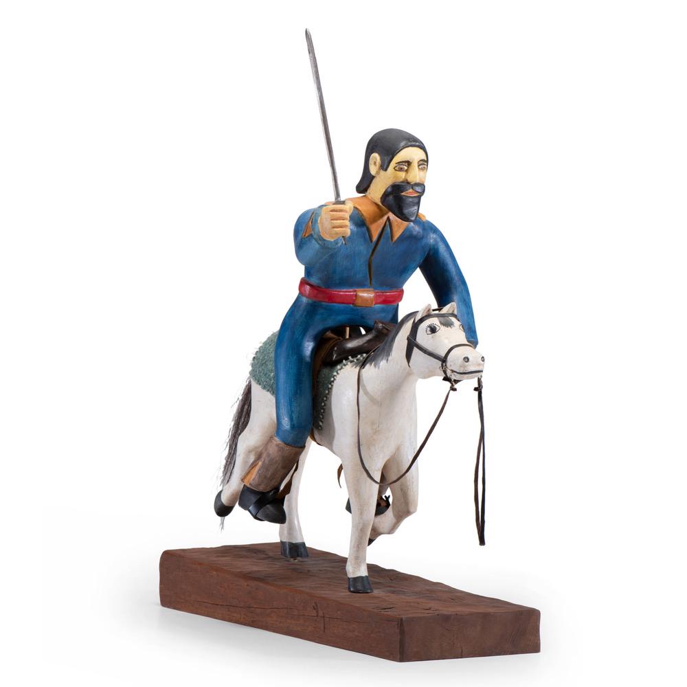 Marco A. Oviedo (New Mexican, 20th century) Wood: Marco A. Oviedo (New Mexican, 20th century) Wood Sculpture, From the Collection of Robert B. Riley, Urbana, IL man wearing blue clothes brandishes a sword; he rides a white horse; sculpture is carved 