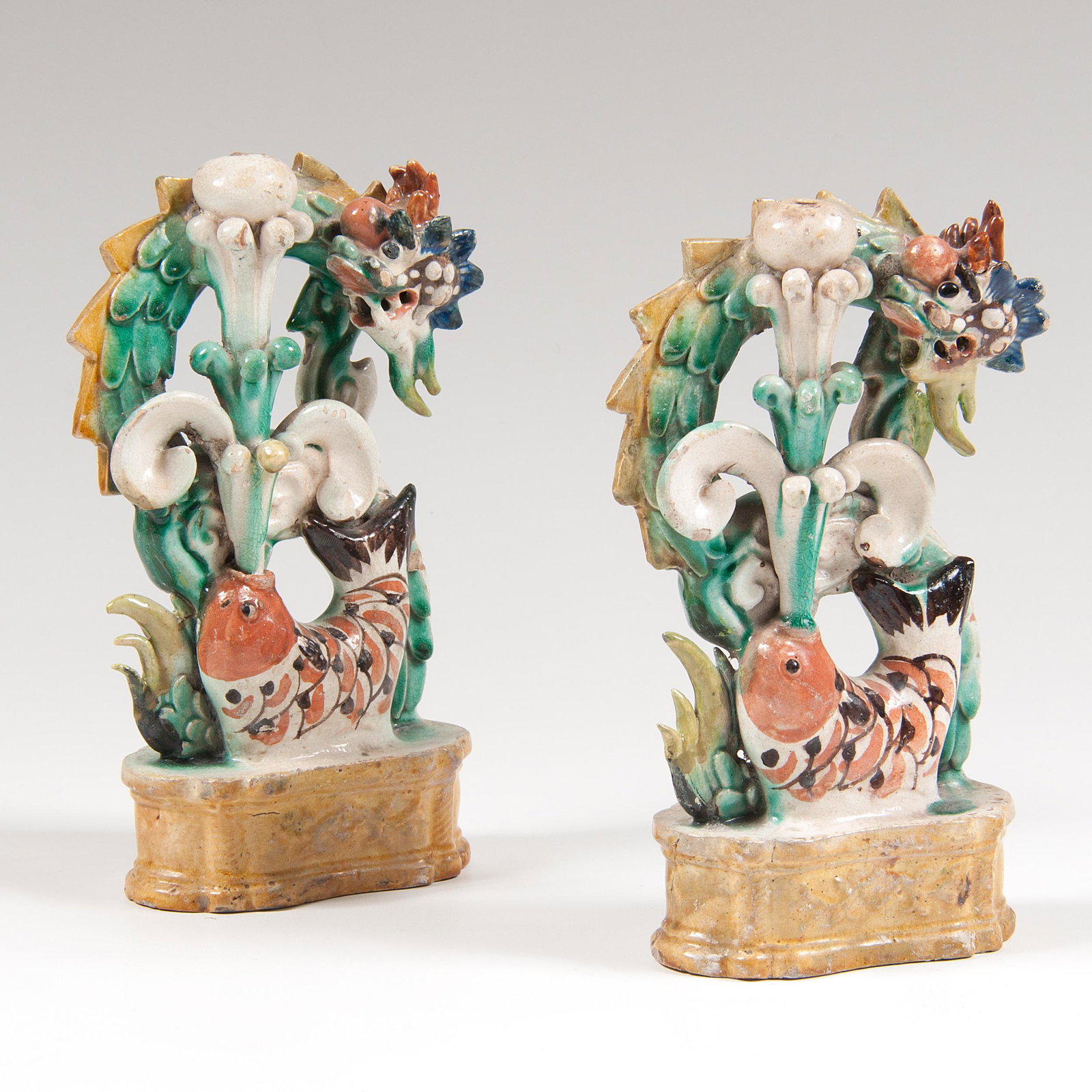 Pair Chinese Polychrome Earthenware Dragons: Pair Chinese Polychrome Earthenware Dragons Chinese. A pair of polychrome earthenware dragons behind a fish spouting water, resting on plinth and with painted marks to undersides; each ht. 8, wd. 5, d