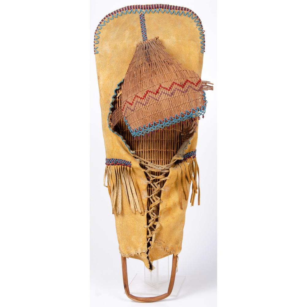 Paiute Beaded Hide Cradle with Basketry Visor: thread-sewn and beaded in colors of red and blues; body of cradle crafted of wood reeds, length 27 in. x width 10 in. early 20th century Provenance: Deaccessioned From the Hopewell Museum, New Jersey