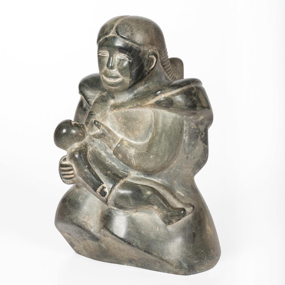 Yougayougaosee (Inuit, b. 1910) Soapstone Carving: soapstone carving depicting a mother feeding a baby she is holding; signed on base with syllabics and disc number; height 12.5 in. x length 8 in. x width 4.25 in. second half 20th century