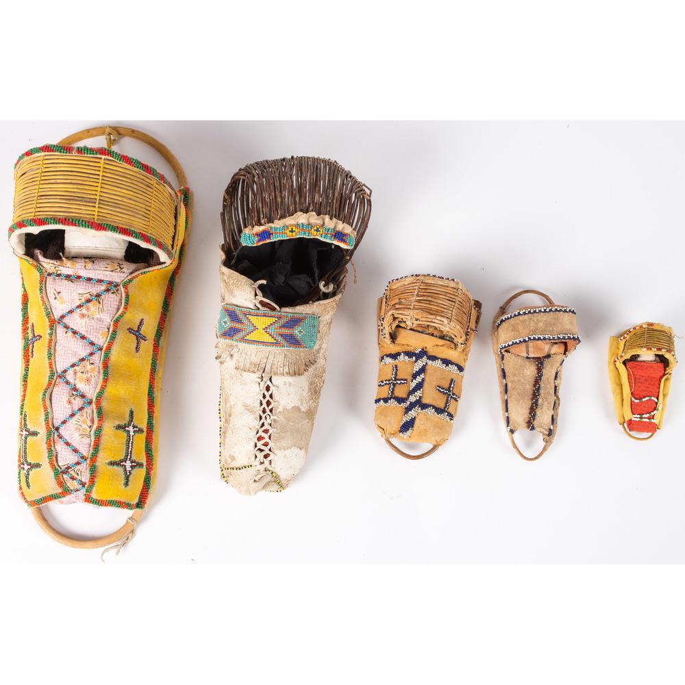 Apache and Paiute Beaded Toy Cradles: lot of 5, the largest with yellow pigment on hide, basketry visor, cloth doll, length 17.25 in., PLUS two smaller Apache cradles with basketry visors, lengths 7 in. and 4.75 in.; PLUS an Apache crad