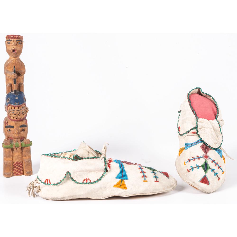 Northern Plains Beaded Hide Moccasins and Northwest: Northern Plains Beaded Hide Moccasins and Northwest Coast Model Wood Totem Pole lot of 2, include a thread and sinew-sewn pair of moccasins; "Peter Pan"-cut cuffs edge beaded in translucent green, len