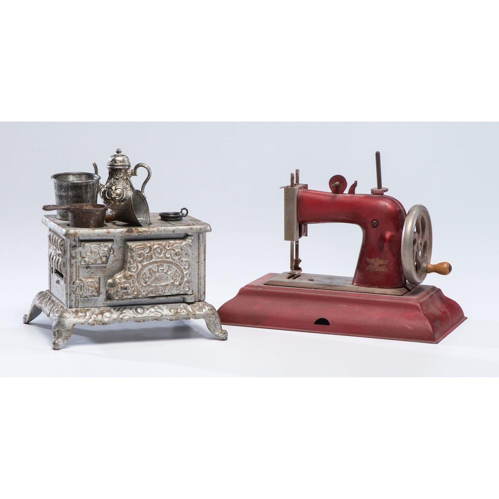 An Eagle Toy Stove and Casige Toy Sewing Machine: An Eagle Toy Stove and Casige Toy Sewing Machine 20th Century stove with five accessories. Height of larger 7 1/2 inches.