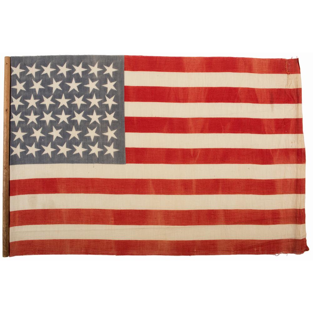 40-Star American Parade Flag: 40-Star American Parade Flag Cotton printed parade flag, 14.75 x 22 in., with 40 stars arranged in 7/6/7/6/7/6 horizontal rows. Attached to 15 in. dowell. South Dakota, the 40th state, joined the Unio