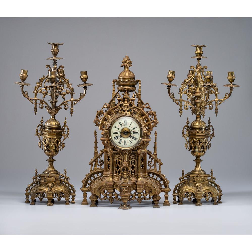 A Gothic Style Bronze Clock Garniture: A Gothic Style Bronze Clock Garniture Continental, 19th Century works marked RR and 4186. Height of candelabra 25 5/8 inches. Height of clock 24 inches.