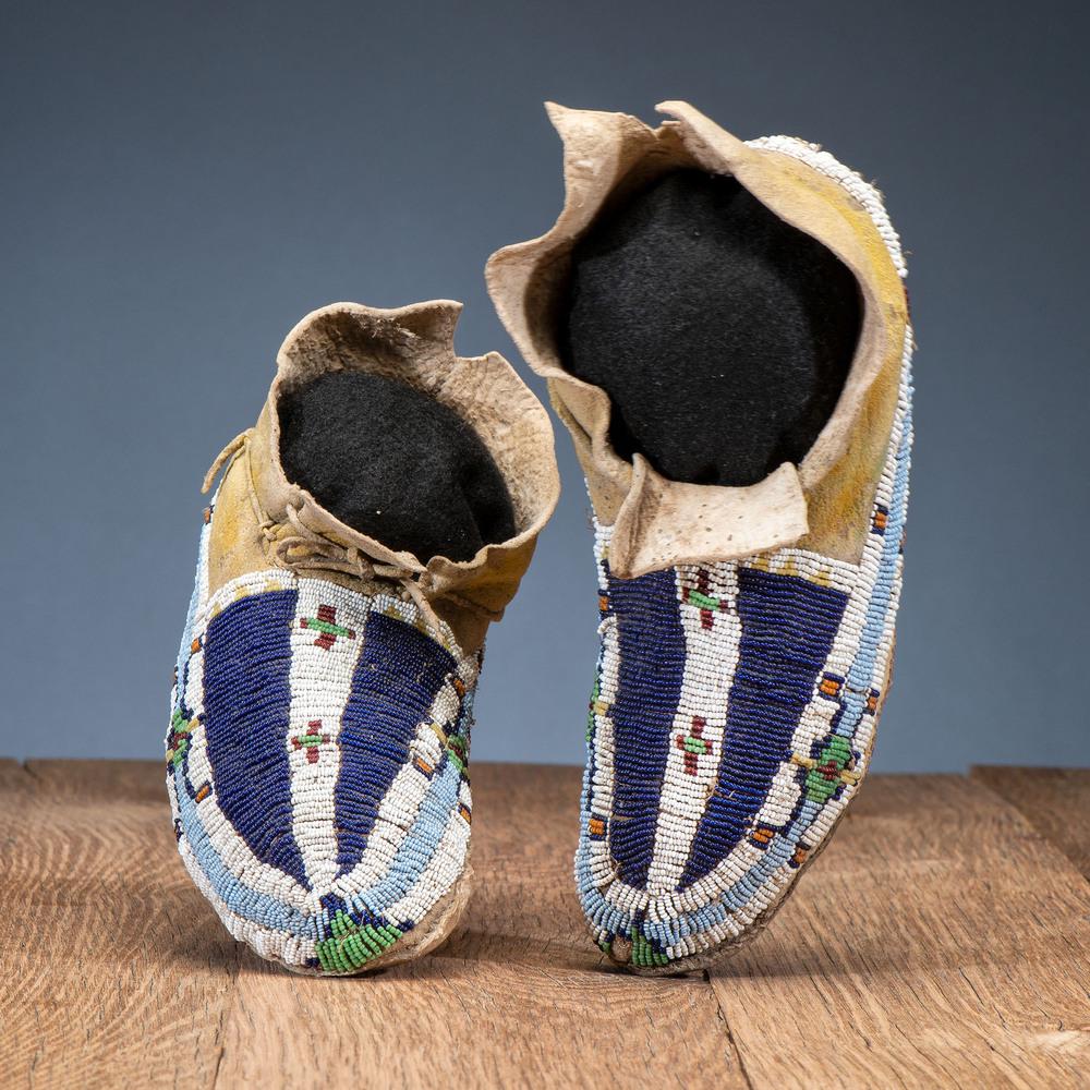 Cheyenne Youth Beaded Hide Moccasins: Cheyenne Youth Beaded Hide Moccasins sinew-sewn on soft hide with yellow pigment; beaded geometric designs in colors of navy blue, light blue, orange, yellow, pea green, translucent red, and white; le