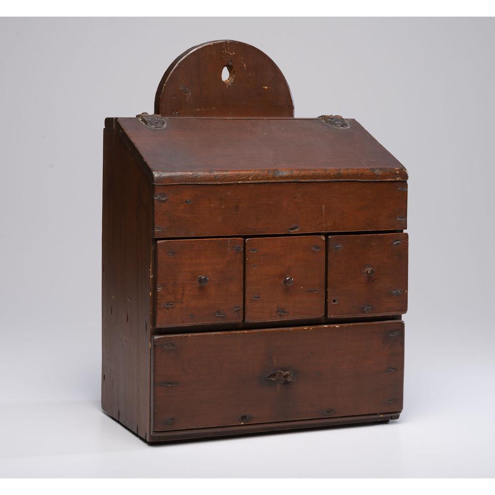 A Hanging Spice Box in Walnut: American, 19th Century with a slant lid and four drawers. Height 17 1/2 x width 12 1/2 x depth 7 1/4 inches. Provenance: Property from the Collection of Judith & Gary Gay, Morrow, Ohio