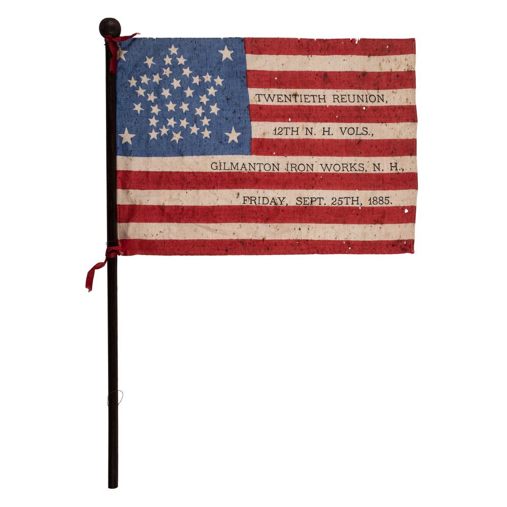 38-Star 12th New Hampshire Reunion Flag: Printed flag on silk, 6.5 x 9.5 in.; original 14.5 in. staff with red ribbon ties. Great Star pattern with four outlying stars, flanked by star in each corner. Overprint: "Twentieth Reunion, 12th NH V