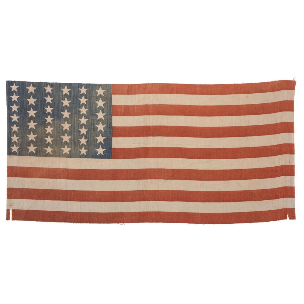 39-Star American Flag: Printed flag on cotton, 12 x 25 in. Three vertical rows with six large stars and three with seven smaller stars, creating columns of equal height. Elongated stripes. Commemorates North Dakota statehoo