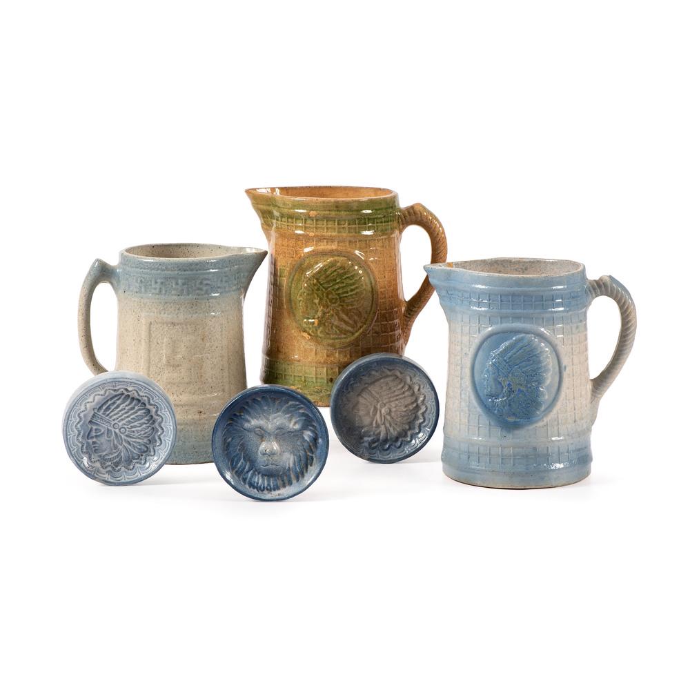 Six Pieces of Clay City Pottery: Indiana, Early 20th Century including three molded pitchers, two with Indian heads, one with swastika and three trivets. Height 10 1/4 inches.