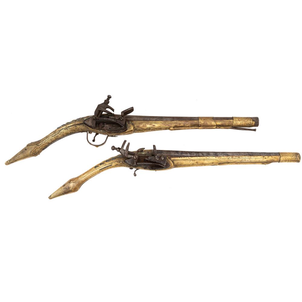 Pair of Albanian Rat Tail Flintlock Pistols: .65 caliber, 11.5" barrels, no S/N. Brass full stocks in the distinctive Balkan style with arabesque motifs throughout. Miquelet-style locks with grooved frizzens.