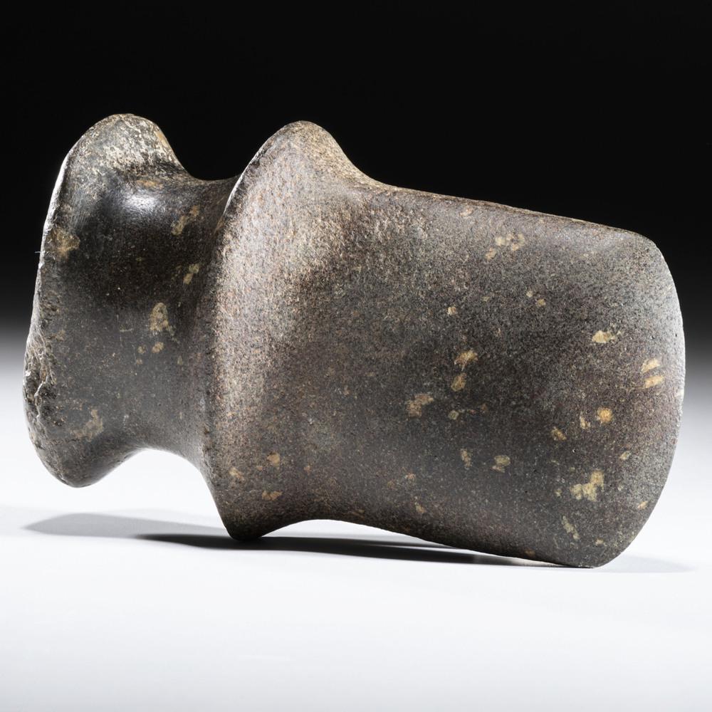 A Porphyry Michigan Barbed Axe, 6-1/4 in.: Archaic Period, 8000-500 B.C. Sigwan, Wisconsin length 6-1/4 in. This full-grooved axe is made from green porphyry. The bit is large in proportion to the entire axe. Collection History: The label on