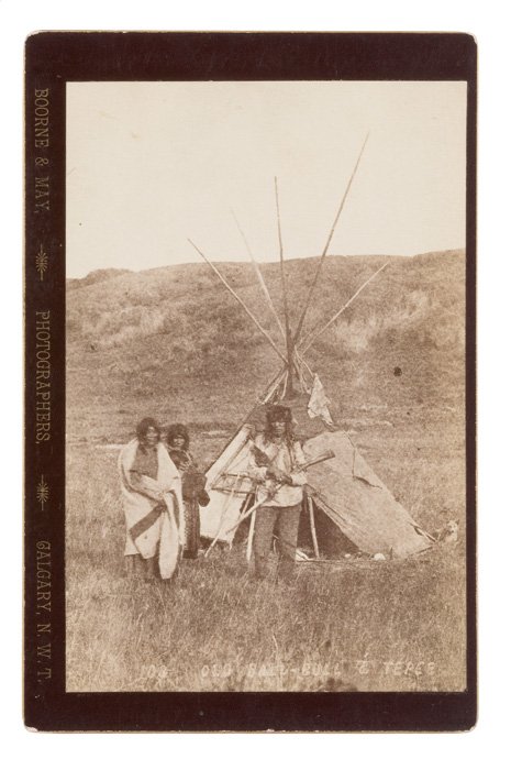 Bourne and May Cabinet Card of Old Bald Bull and T: Bourne and May Cabinet Card of Old Bald Bull and Tepee, ca 1880s, identified in the negative and with their Calgary, North West Territory imprint. Bald Bull cradles a tack-decorated trade musket. A 