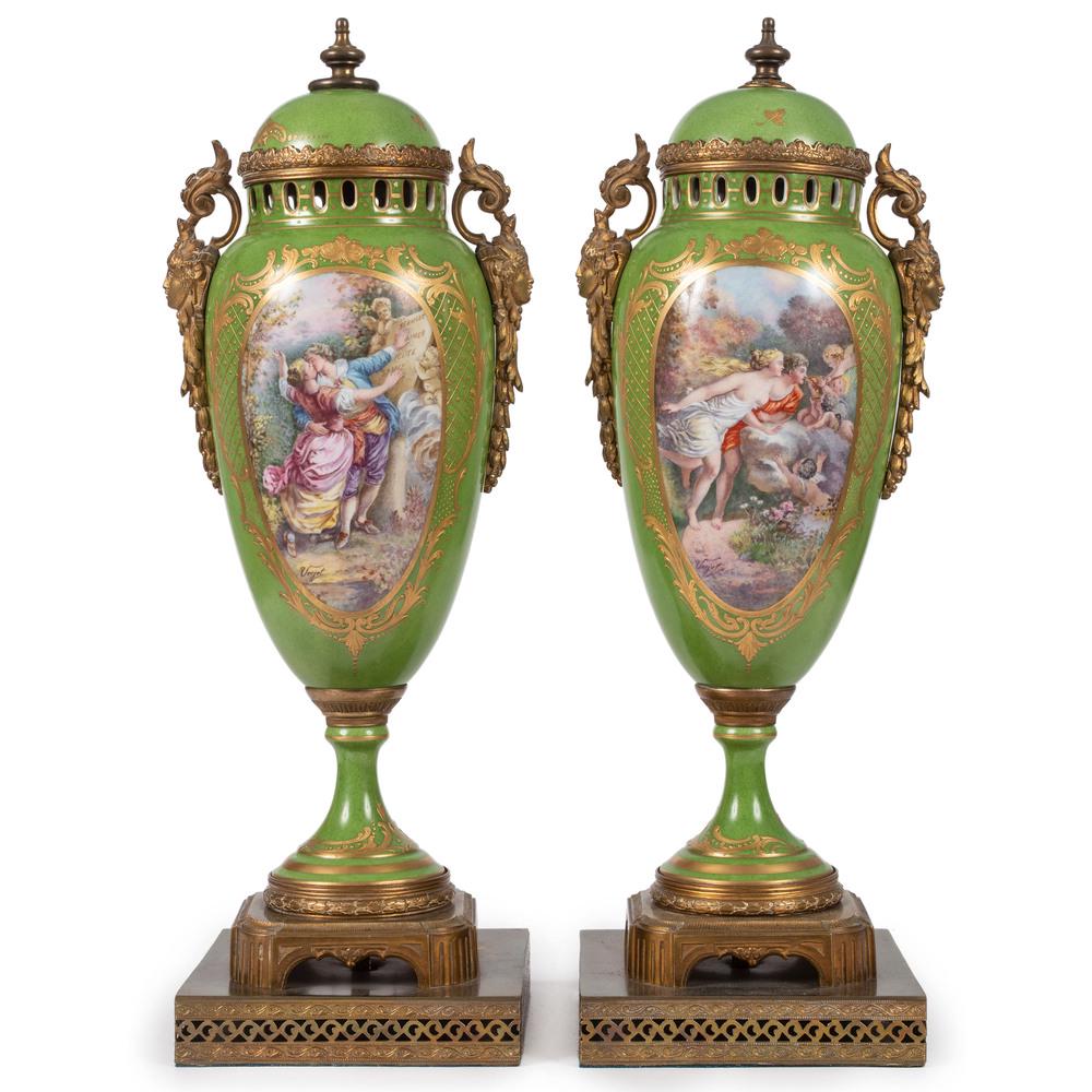 A Pair of Porcelain Urns in Green with Ormolu Mounts: French, 19th/20th Century the lidded urns with heightened gilt and hand-painted decoration, each raised on a shaped base. each signed Vejot on front. Height 20 inches. Provenance: Property from the 