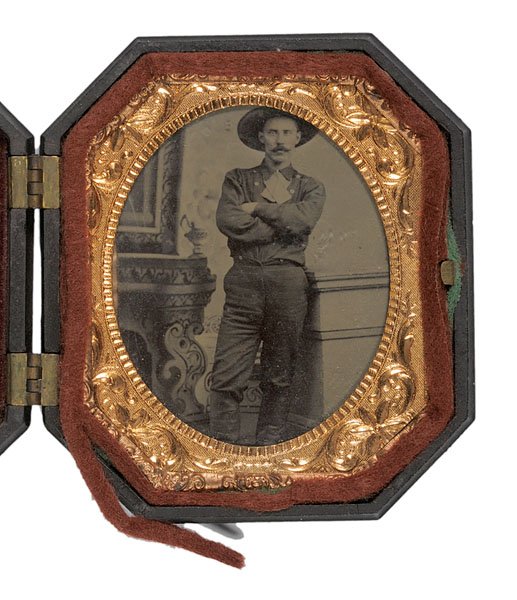 Tintype of a Western Dude, : Tintype of a Western Dude, ca. 1880s – 1890s, the mustachioed subject striking a jaunty studio pose in his wide-brimmed hat, double-breasted shirt and knee-high boots. Behind stamped brass mat in 