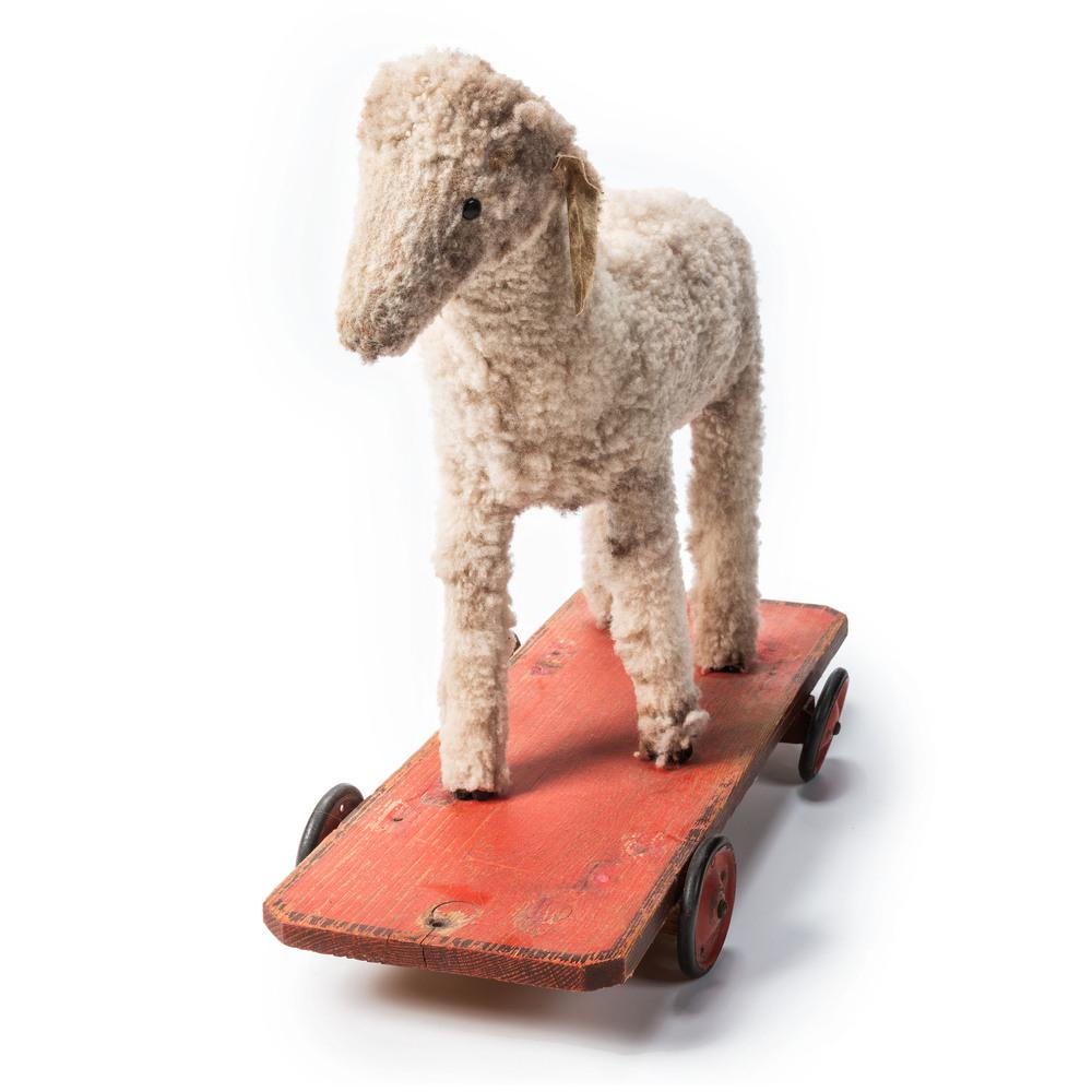 A Large Wooly Sheep Pull Toy: A Large Wooly Sheep Pull Toy 20th Century fixed on a painted wooden platform with red metal wheels. Height 20 1/2 x length 22 1/2 inches. Property of the late Karen Tosterud, Bellaire, Michigan We are