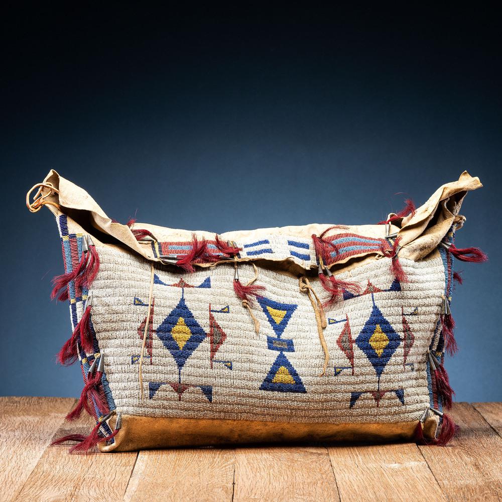 Sioux Beaded Hide Possible Bag: sinew-sewn, panels beaded using glass bead colors of white, medium blue, dark blue, greasy yellow, red white-heart, and cut marcasite; further embellishments of tin cones filled with red-dyed horsehai