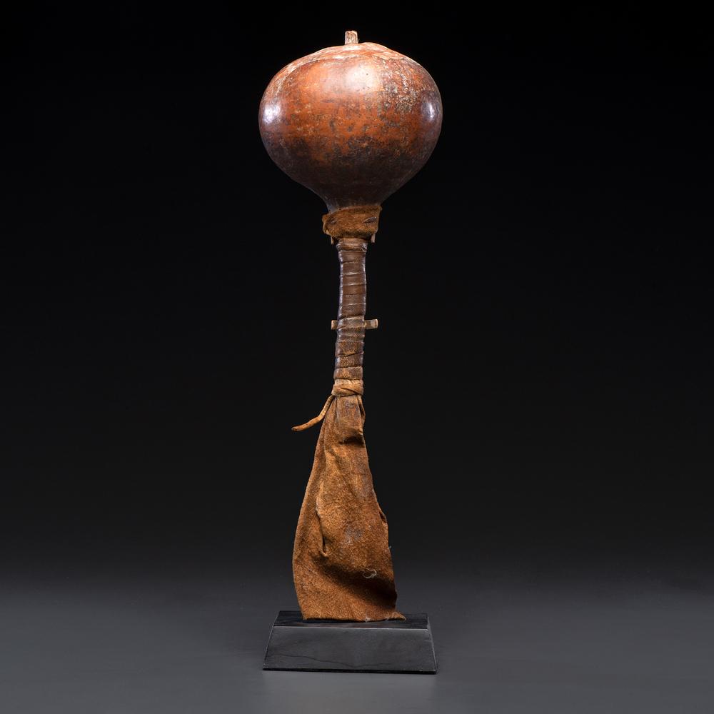 Southwestern Gourd Rattle with Buffalo Hide, From the: remnants of white paint on gourd; wood handle wrapped with buffalo hide overall height 16.5 in. fourth quarter 19th century Without Stand. Provenance: From the Collection of Dick Jemison, Alabama