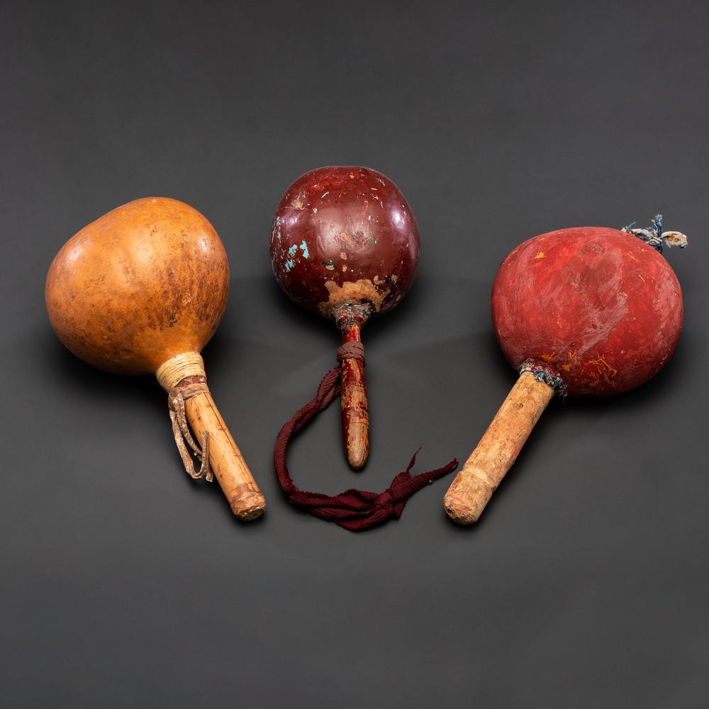 Trio of Pueblo Painted Gourd Rattles, From the: lot of three, includes two rattles painted red and one painted brown; lengths 9 in., 9 in., and 10.5 in. second quarter 20th century
