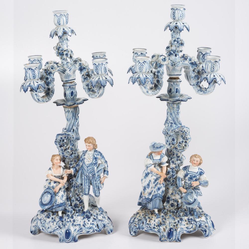 A Pair of German Blue and White Porcelain Candelabras: A Pair of German Blue and White Porcelain Four Light Candelabras Late 19th Century having brown crossed sword marks to undersides. each modelled as a courting couple arranged around a flower-encrusted